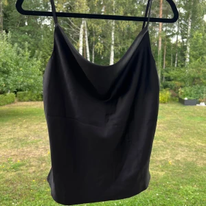 Svart linne i satin - Ett svart linne i satin från Gina Tricot. Linnet är i storlek 36 men passar bra till 34 också 🤍 Endast använt en gång 🌷 Justerbara axelband.  Längd: 44 cm