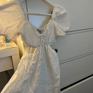 Vit klänning från Chiquelle - Säljer en superfin vit klänning från Chiquelle i storlek XS. Den har puffiga kortärmar och en söt knytning framtill. Perfekt för skolavslutning eller stundent. Klänningen är i nyskick🩷