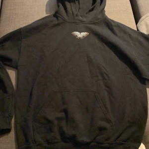 Svart hoodie med fjärilstryck - Säljer en svart hoodie med ett coolt fjärilstryck både fram och bak. Den är perfekt för höst och vinter med sin mysiga och varma känsla. Hoodien har en klassisk passform med en stor ficka fram och en bekväm huva. Perfekt för chill dagar eller när du vill ha en avslappnad stil. 🦋 Snöret som tightar till hoodien är borta men den fungerar som den ska👍