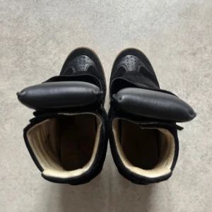 Svarta sneakers med kilklack - Isabel Marant Bekett Sneakers med kil i läder Flera material: lammskinn och mocka kalvskinn Runda tår Kardborreband Vadderad tunga Vävd etikett Mjuka lädersulor och foder Yttersulor i gummi  Klackhöjd: 5 cm / 2 in.  Stil: BK0010FA-A1E19S BEKETT  100 % kalvskinnsläder