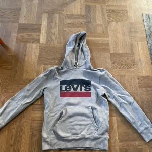 Grå Levis hoodie  - Säljer nu min sjukt snygga gråa Levis hoddie i storlek S skick 7-10 sömmen vid fickan har gått upp lote annars i bra skick. Hör av dig om fler frågor!