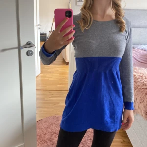 Grå och blå klänning - Säljer en superfin klänning i grått och blått. Den har en tight passform upptill med en ribbad midja som ger en snygg siluett. Klänningen är långärmad och perfekt för både vardag och fest. Materialet känns mjukt och bekvämt.