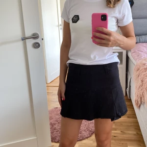 Svart kortkjol - Säljer en snygg svart kortkjol som är perfekt för både vardag och fest. Kjolen har en enkel design med en normal passform och är gjord i ett bekvämt material. Den är lätt att matcha med olika toppar och accessoarer.