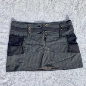 Minikjol - Skitsnygg kort kjol i blandat jeansmaterial som tyvärr blivit för liten. Midjemått: 41 cm. Längd: 32 cm. 