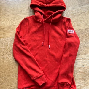 Röd luvtröja husky wear  - Röd tröja, använd ca 3ggr. Småhål på tröjans snören.