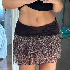 Lågmidjad kort kjol - Säljer denna lågmidjade korta brun blommiga kjol!! Så jävla snygg men den är tyvärr lite för liten på mig. Älskar lågmidjat och tycker de är så snyggt med den tjocka bruna kanten. Väldigt mjuk och har även en  silkes kjol under så man inte ser igenom