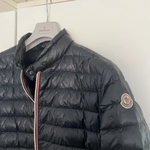 Mörkblå Moncler jacka  - Herr jacka  Storlek 2 (motsvarar ungefär s/m) Liten uppslitning i den vänstra fickan (inget som syns utifrån) *se sista bilden Jättefint skick!