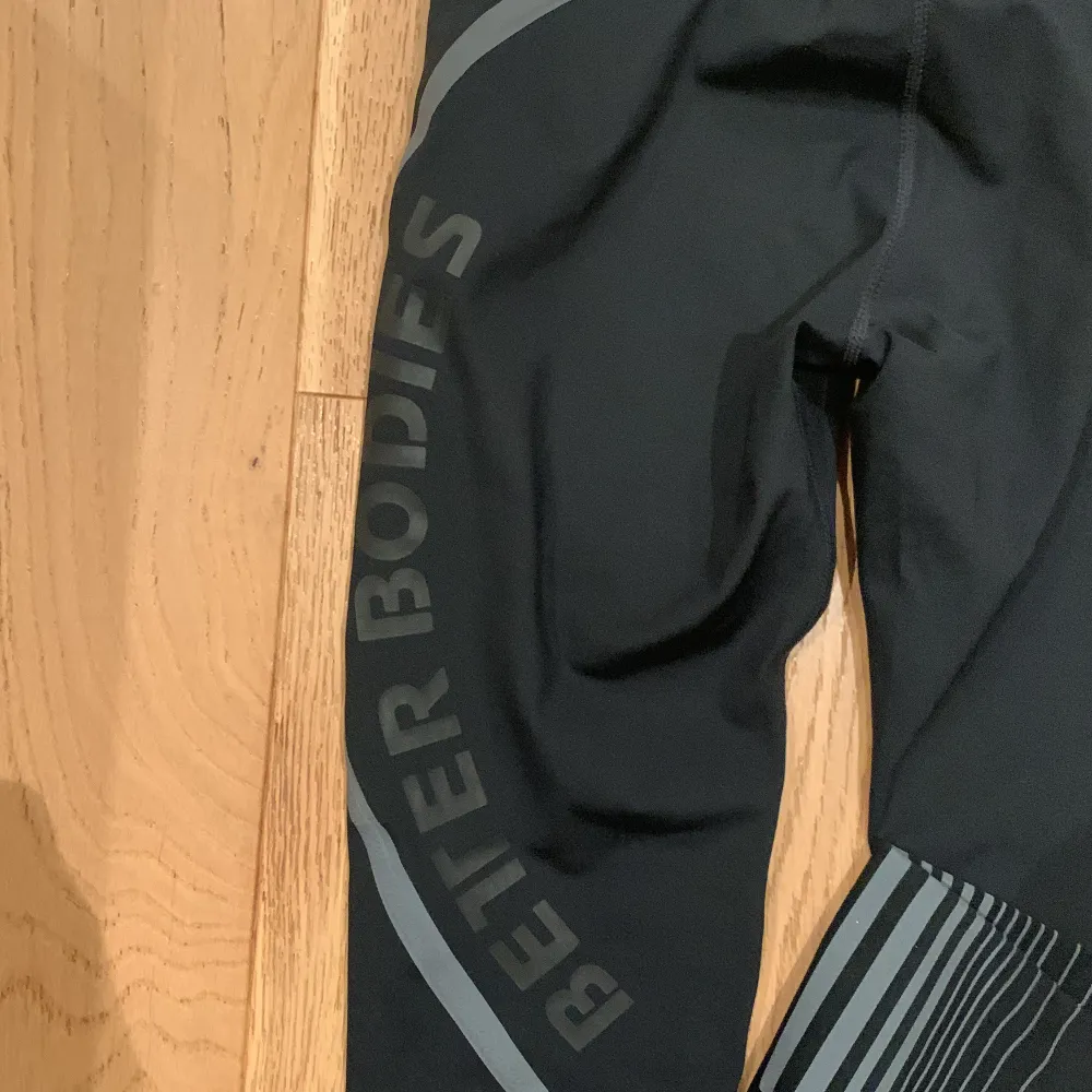 Säljer ett par svarta träningtights från Better Bodies i storlek XS. De har en normalhög midja och grå detaljer längs benen samt Better Bodies-logga. OBS små! . Sportswear.