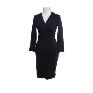 Svart klänning från Tiger of Sweden - Säljer en elegant svart klänning från Tiger of Sweden i storlek 34. Klänningen har en v-ringad omlottdesign och långa ärmar, vilket ger en stilren och sofistikerad look. Perfekt för höst- och vinterevenemang. Den är i nyskick och passar utmärkt för både fest och formella tillfällen.