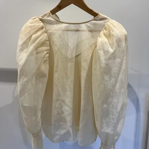 Beige blus från & Other Stories - Säljer en superfin beige blus från & Other Stories. Den har långa puffiga ärmar och en knytning framtill som ger en romantisk touch. Perfekt för både vardag och fest! 💫