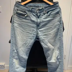 Säljer ett par klassiska Levis 502 jeans i ljusblå denim. De har en normal passform och är perfekta för vardagsbruk. Jeansen har en traditionell femficksdesign och en knappgylf. De är i bra skick och redo för en ny ägare!