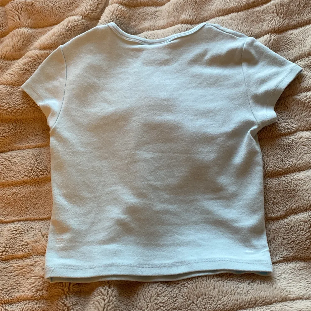 Supergullig ljusblå t-shirt från Bershka med Cinnamoroll-tryck på framsidan. Den har korta ärmar och är perfekt för en avslappnad stil. Texten 'warm heart and wagging tail' ger en extra söt touch. Perfekt för alla Cinnamoroll-fans!💙🩵. T-shirts.