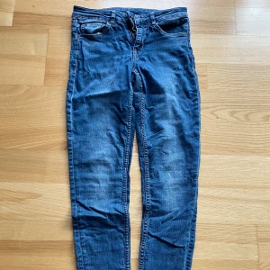 Blå jeansbyxor - Säljer ett par snygga blå jeansbyxor i slim fit. SUPERSTRETCH. De är högmidjade och har en klassisk femficksdesign. Välanvända därav det låga priset.