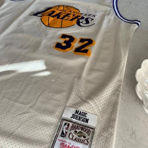 Lakers tröja 32 Magic Johnson - Lakers linne 32 Johnson . Alla siffror och Lakers logon är broderade . Mitchell & Ness Hardwood classic. 52 cm över bröstet - 104 cm totalt .