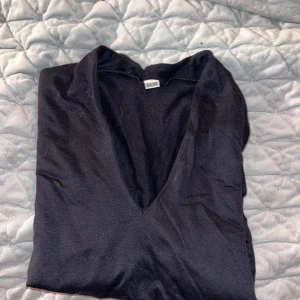 Svart långärmad topp - Säljer en stilren svart långärmad topp i storlek 34/36. Den har en v-ringad design som ger en elegant touch. Perfekt för både vardag och festliga tillfällen. Toppen är i bra skick och redo för en ny ägare!