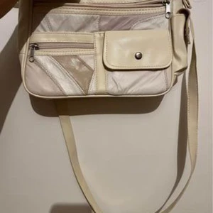 Beige axelväska i Skin - Säljer en snygg beige axelväska i skinn med flera praktiska fack och dragkedjor. Väskan har en justerbar axelrem och en stilren design med olika nyanser av beige. Perfekt för vardagsbruk eller en dag på stan!