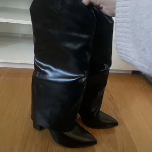 Svarta stövlar i skinn - Säljer ett par snygga svarta stövlar i skinn med spetsig tå. Perfekta för höst och vinter, dessa boots har en stilren design som passar både till vardags och fest. De är i mycket bra skick och redo att användas direkt. Perfekt för att ge din outfit en extra edge!