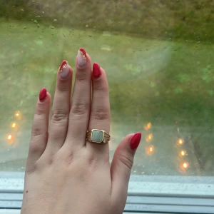 Guldring med grön sten - Snygg guldring med en stor, fyrkantig grön sten i mitten. Perfekt för att ge en touch av elegans till vilken outfit som helst. Ringen har en enkel men stilren design som passar både till vardags och fest. Ett måste för smyckesälskare!