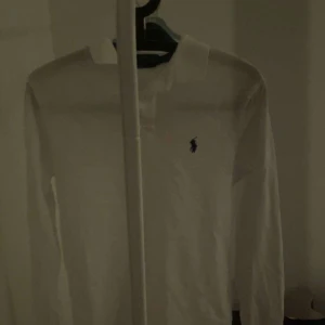 Vit långärmad pikétröja från Ralph Lauren - Säljer en klassisk vit långärmad pikétröja från Ralph Lauren i storlek XS. Tröjan har en broderad logga på bröstet och är i ett snyggt slim fit-snitt. Aldrig använd eftersom jag köpte fel storlek därav skicket 10/10. Kvitto medkommer vid köp!