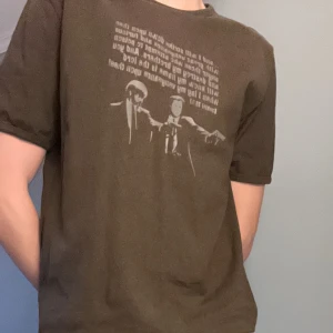 Sjukt snygg Pulp ficton tröja  - Säljer en brun sjukt unik och stilren tröja med den klassiska Pulp ficton scenen som motiv. Perfekt för vardagsbruk eller en avslappnad dag ute. T-shirten är i bra skick och har en normal passform. Funkar både för S eller M 