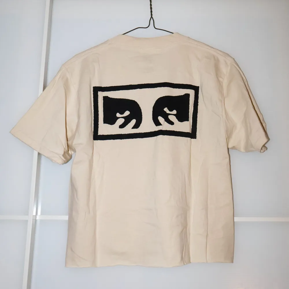 Säljer en beige t-shirt från Obey i storlek S. Den är gjord av 100% bomull och har ett svart tryck på både fram- och baksidan. Perfekt för en avslappnad stil och passar till alla säsonger. T-shirten är i mycket bra skick och redo för nya äventyr! . T-shirts.