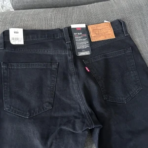 Oanvända Svarta Levi's 511 - Säljer ett par svarta Levi's jeans i slim fit. De är i nytt skick och har en klassisk design med fem fickor och en snygg läderetikett bak. Perfekta för både vardag och fest! 🖤