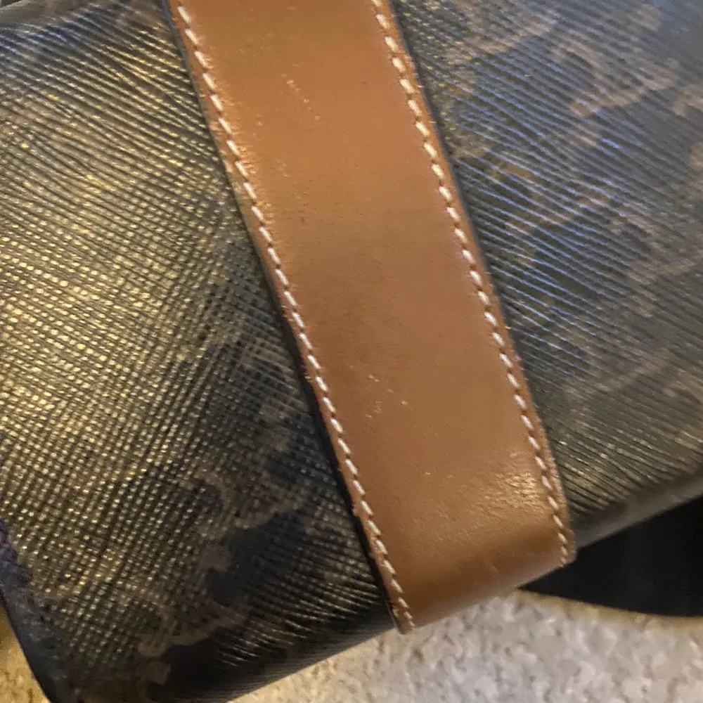 Säljer en elegant Celine plånbok i svart och brunt med guldiga detaljer. Plånboken har ett klassiskt mönster och är tillverkad i skinn. Perfekt för att hålla ordning på kort och kontanter med stil. Kommer med originalförpackning. Väldigt fin på utsidan men märken på insidan som bild visar. Kommer med låda påse och tag.. Accessoarer.