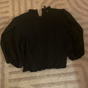 Svart blus - Svart smockad blus med volang kant från h&m, storlek xs/36. Har även stora puffärmar. Passar till fina sammanhang som till exempel dop eller middagar! Denna är ärvd från min moster! Men aldrig använd🤍 pga för stor!⭐️ ingen lappar kvar men cirka 1 år gammal!👸🏼 inga hål eller liknande, hoppas den hittar ett fint hem!