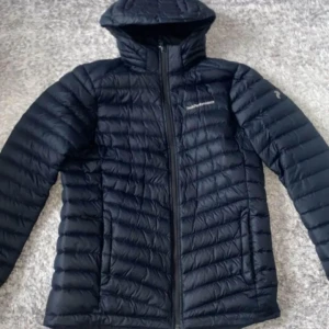 Svart dunjacka från Patagonia - Säljer en svart dunjacka från Patagonia i mycket bra skick. Jackan har en snygg quiltad design och är perfekt för kalla dagar. Den har en dragkedja framtill och en huva för extra värme. Perfekt för både vardag och utomhusaktiviteter! Pris kan diskuteras