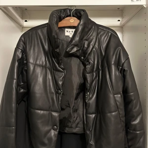 Svart vinterjacka puff från NA-KD - Stor mjuk puffig varm vinterjacka med knappar fram och högre krage! Saknar en knapp längst ner men går att sy till eller låta vara då man kan stänga den ändå!