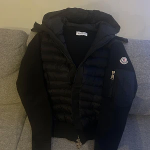 Cardigan från Moncler - Säljer en snygg svart pufferjacka från Moncler. Jackan har en quiltad design med dragkedja och en praktisk ficka på ärmen. Perfekt för kyliga dagar och ger en stilren look. Passar både till vardags och lite finare tillfällen. använd en till två gånger Max ,, säljer för det är inte min typ längre,,passar både storlek S och M 🖤