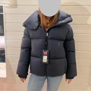 Colmar Originals Oversized dunjacka - Jättesnygg mörkblå dunjacka från Colmar Original i Oversized modell med maxi-krage i storlek 34. Jackan är perfekt för vintern med sin tjocka vaddering och höga krage. Den har en dragkedja framtill och långa ärmar. Jackan är i nytt skick med etikett kvar. Perfekt för kalla dagar! ❄️