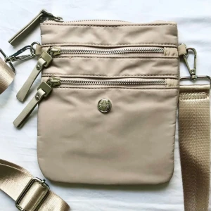 Snygg axel väska - Fin axelväska med många fickor och tryck på insidan. Bandet är justerbart. Nyskick! Mått: höjd 20 cm, bredd 17 cm