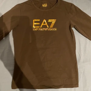 Lång t-shirt EA7 Emporio Armani - Säljer nu min svarta långa t-shirt från Emporio Armani (EA7) använd några gånger men inga tecken, kom pm om ni vill ha bild på de. Märket är guld och storleken är 150cm, kom privat om ni har frågor!