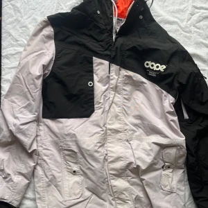 Svart och vit jacka från Dope - Säljer en snygg svart och vit jacka från Dope i storlek L. Jackan har en cool design med dragkedja och knappar, samt praktiska fickor framtill. Perfekt för vinter och skidsemester med sin bekväma passform. Passar både till skidsemester eller som vanlig vinterjacka! Säljer ett par tillhörande byxor på min profil, om man vill ha båda är det möjligt med paketpris!