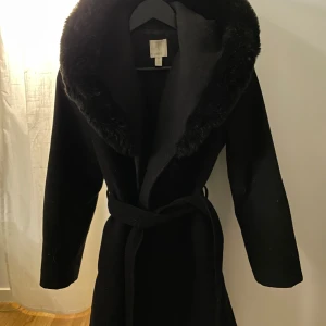 Svart kappa med luva - Säljer en elegant svart kappa med en luva. finns fickor på sidorna. 