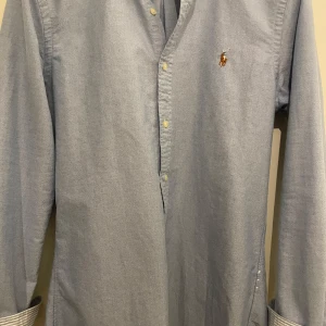 Blå skjorta från Ralph Lauren - Säljer en stilren ljusblå skjorta från Ralph Lauren i storlek M. Skjortan är i slim fit och har långa ärmar med knappar. Perfekt för både vardag och fest! 🕺