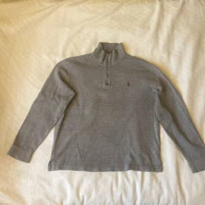 Ralph Lauren Quarter Zip - Snygg raffe quarter Zip som är perfekt för hösten och vintern eftersom den är lite mörkare och väldigt varm. Knappt använda och har varken defekter eller tecken på användning. Jag är 178 och den är lite stor på mig så är du 180 eller lägre borde den passa svinbra