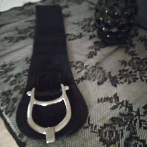 Svart bälte med silverdetalj - Snyggt svart bälte med en cool silverfärgad spänne. Perfekt för att ge din outfit en edgy touch. Passar bra till både jeans och klänningar. Ett måste för alla som gillar att sticka ut!