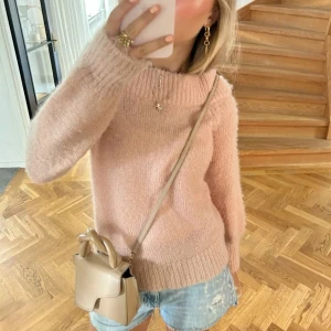 Rosa stickad tröja - Mysig rosa stickad tröja i fluffigt material. Perfekt för kyliga dagar med sin varma och bekväma passform. Långärmad design med ribbade muddar vid ärmslut och nederkant. Lite nopprig pga användning men fint skick.