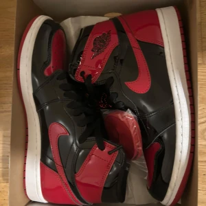 Nike Air Jordans i svart och rött - Säljer ett par snygga Nike Air Jordans1 i svart och rött. Skorna är använda två tre gånger och kommer med extra röda skosnören. 