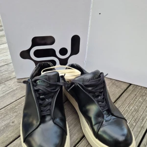 Svarta sneakers med vit sula - Säljer ett par Eytys Doja Leather black skor i gott skick Stl 43 Robusta low-top sneakers i glänsande svart läder. Har en förhöjd tåhätta, anpassade Eytys gummisulor och dold öppning. Med fotvalvsstöd och korkinnersulor för maximal komfort. 