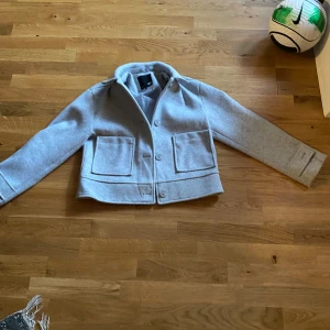 Ljusgrå kappa - Denna fina kappa säljer jag då den inte passar mig, den är i nyskick förutom att en knapp saknar vid ena handleden, men det är lätt att sy dit och syns knappt