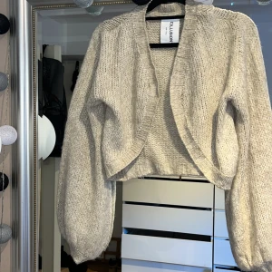 Stickad Kofta S - En beige stickad bolero från märket Collusion i storlek S, går att knäppa. Använd 1 gång 
