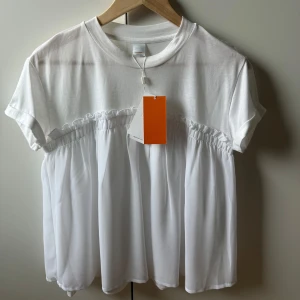 Hugo Boss t shirt - Superfin t shirt med volang, aldrig använd och prislappen kvar. Storlek M 