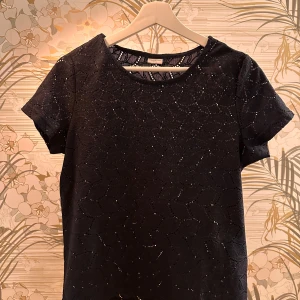 Svart topp - Snygg mörkblå topp med korta ärmar. Perfekt för en kväll ute eller en festlig tillställning. Toppen har en rund halsringning och ett elegant utseende.