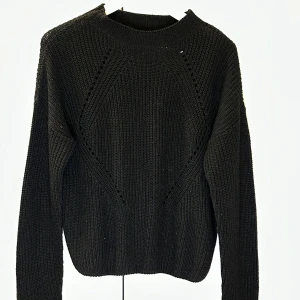 Svart stickad tröja - Säljer en stilren svart stickad tröja med rund hals och långa ärmar. Perfekt för kyligare dagar och enkel att matcha med olika outfits. Tröjan har en klassisk design med ribbade kanter.