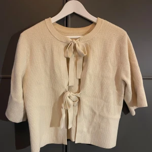 Beige ribbad kofta med knytband - Säljer en stilren beige ribbad kofta med trekvartsärmar och dekorativa knytband framtill. Knappt anvönd och såååå himla fin! Passar xs/s❤️köpt för 600kr