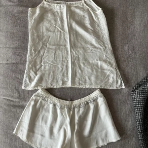 Pyjamasset silke, Intimissimi, S, vit - Pyjamasset (linne+shorts) i äkta silke från Intimissimi i storlek S, vit/creme. Nyskick, använd max 2 ggr. Fina detaljer i spets. 100% silke.   Mått linne:  Längd ca 65 cm enligt bild (justerbar) Byst ca 42 cm Midja ca 42 cm  Mått shorts:  Yttre längd ca 7 cm Inre längd ca 25 cm Midja ca 31 cm (elastisk)  Stuss ca 48 cm