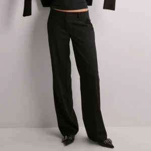 Svarta kostymbyxor - Snygga svarta kostymbyxor med en klassisk passform. Perfekta för en stilren look. Byxorna har en rak stil och är midwaist, vilket ger en bekväm och modern känsla. Gylfen är trasig men inget som stör, går annars att enkelt fixa hos en skräddare